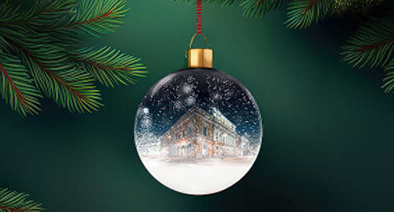 Ett runt julgransornament i glas med en målad vinterscen av Åbo Svenska Teater, omgiven av fallande snö mot en mörkgrön bakgrund. Pyöreä lasinen joulukuusikoriste, jossa on maalattu talvimaisema Åbo Svenska Teaterista, lumisateen ympäröimänä tummanvihreää taustaa vasten. A round glass Christmas ornament featuring a painted winter scene of Åbo Svenska Teater, surrounded by falling snow against a dark green background.